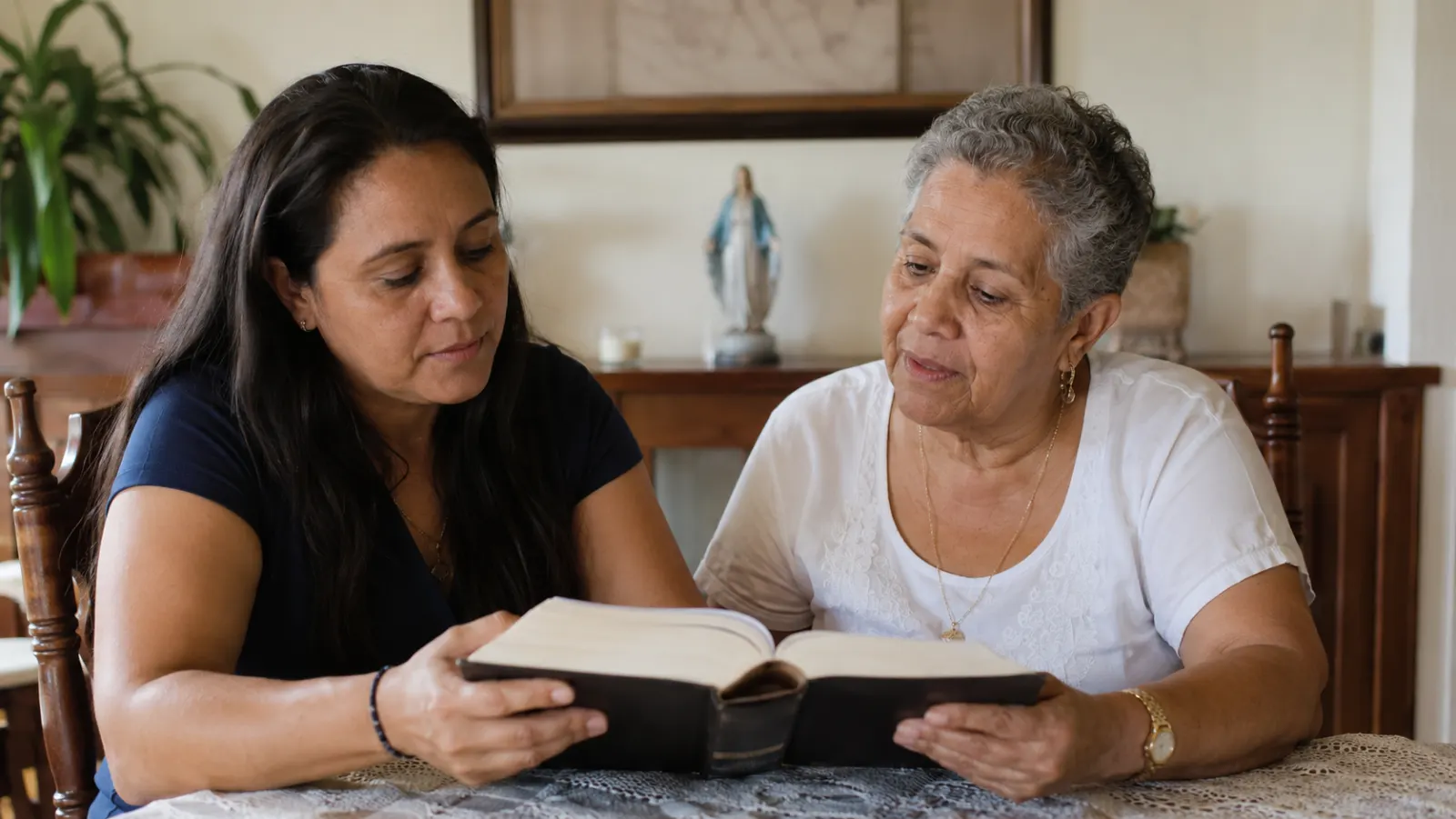 Dos mujeres cristianas latinoamericanas de distintas generaciones leen juntas el Evangelio de Lucas en una mesa familiar.